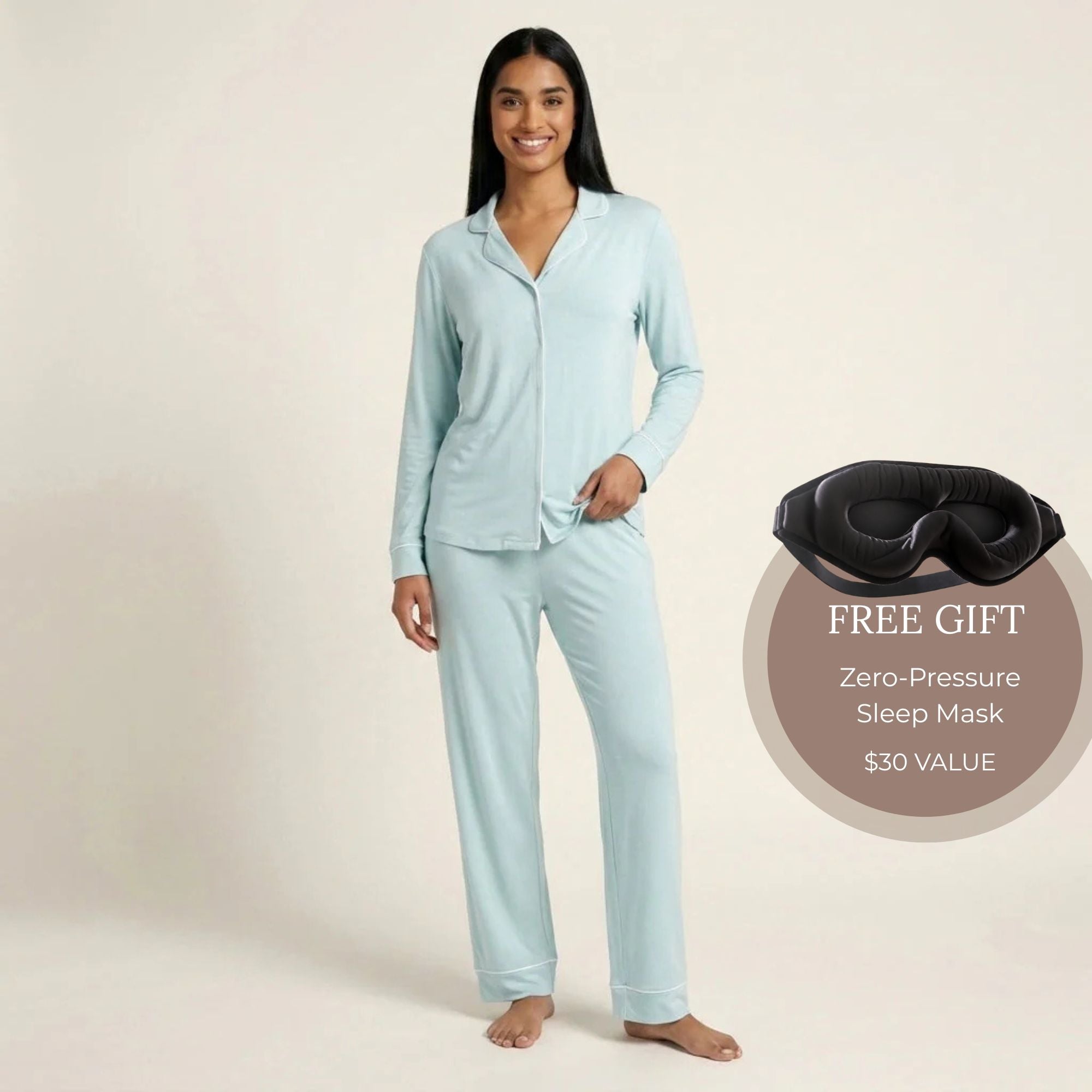 A woman modeling a light blue long-sleeve pajama set with a button-front top and matching pants, standing against a plain beige studio background. Available in Ice Mint XS, Ice Mint S, Ice Mint M, Ice Mint L